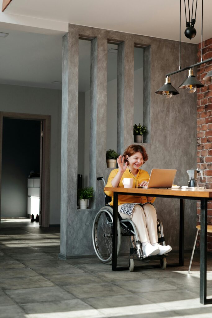 pexels-photo-4064696-4064696 Woman in a wheelchair enjoying remote work and video call at home in a modern interior.